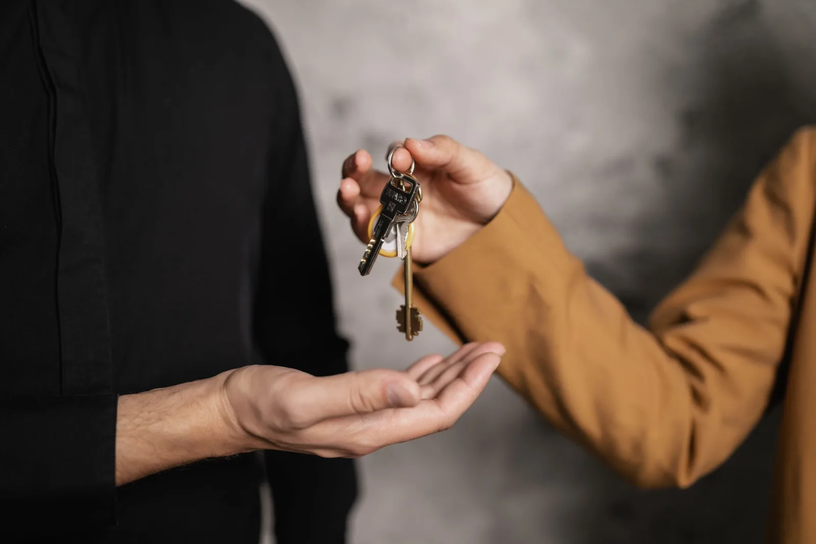 Close-up of one person’s hand passing a set of keys into another person’s open palm