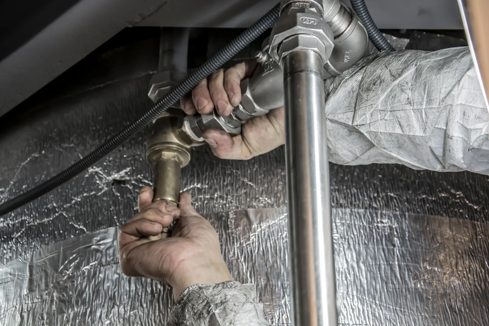 Hands fitting a copper pipe to a joint